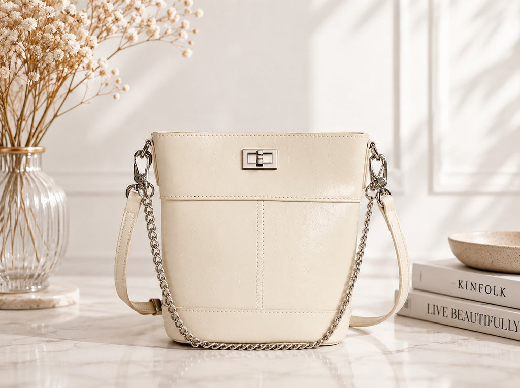 Beige handbag with chain strap on a light surface with decorative items.