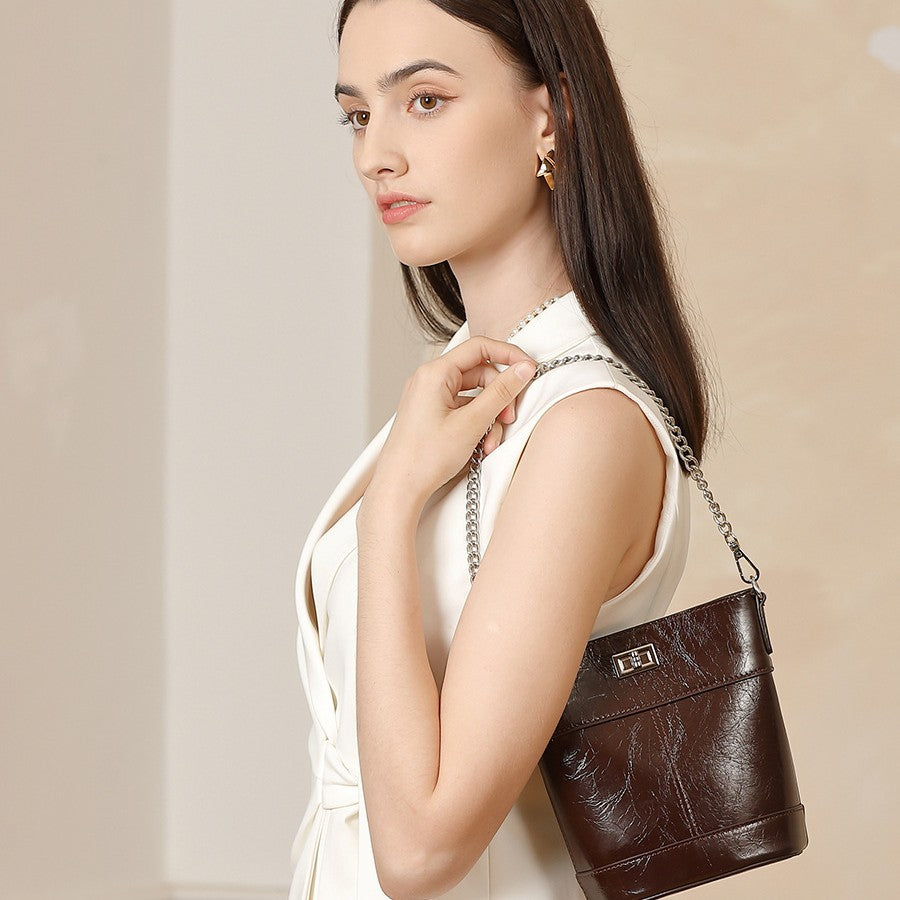 Woman holding a brown leather handbag against a plain background