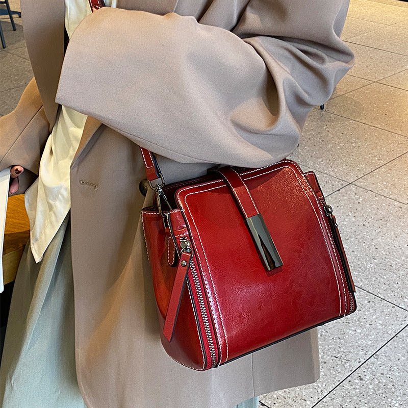 Red handbag held by a person wearing a beige coat.