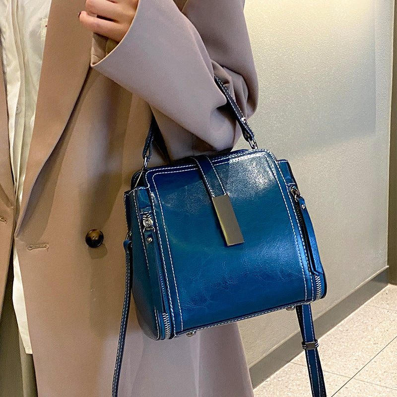 Blue handbag held by a person wearing a beige coat.
