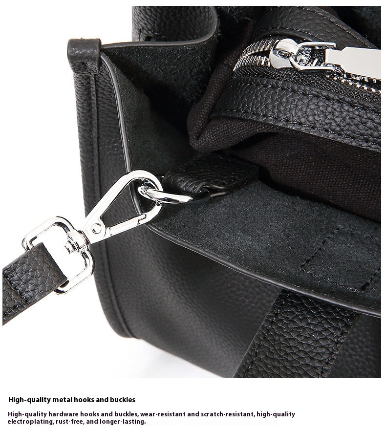 Close-up of a black leather bag with metal hooks and buckles on a white background