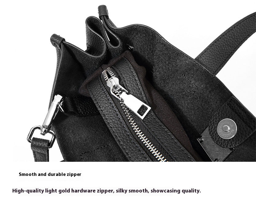 Close-up of a black bag with a zipper and light gold hardware on a white background.