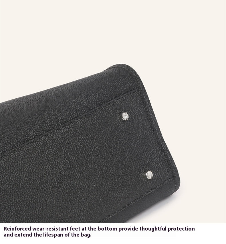 Black leather bag with reinforced wear-resistant feet on a white background