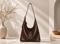 Brown leather handbag on a light wooden surface with a neutral background