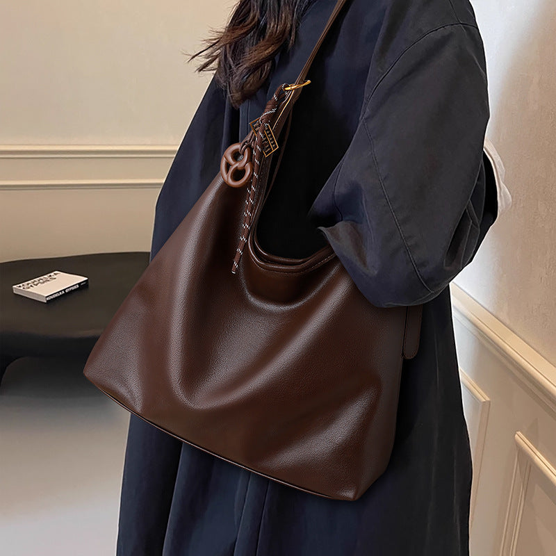 Person holding a brown leather handbag in an indoor setting