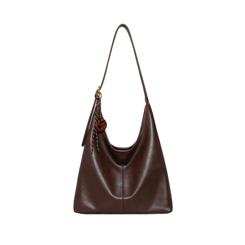 Brown leather handbag with a strap on a light gray background