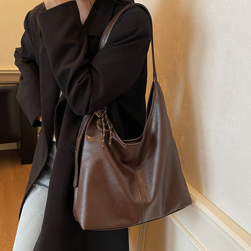 Person holding a brown leather handbag indoors
