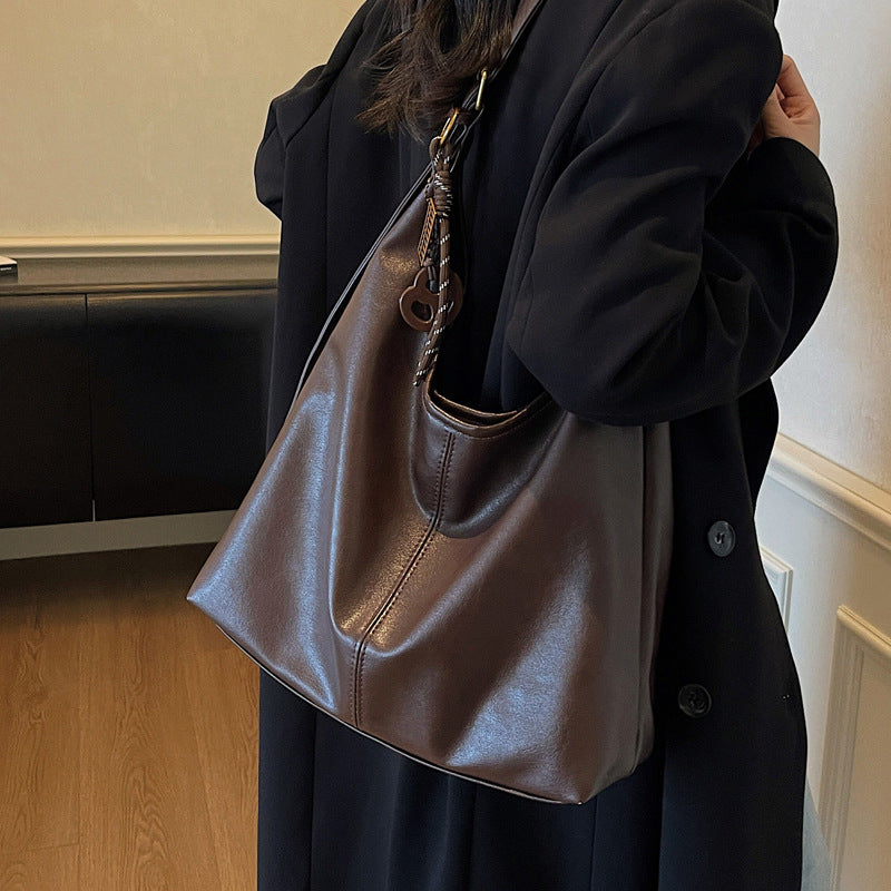 Person holding a brown leather handbag indoors