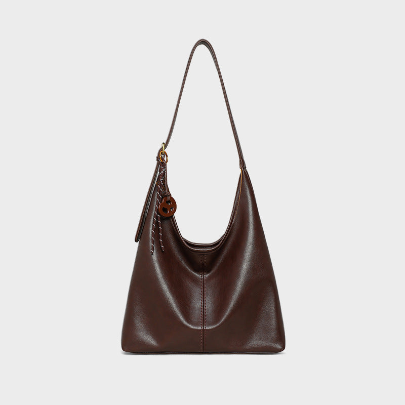 Brown leather handbag with a strap on a light gray background