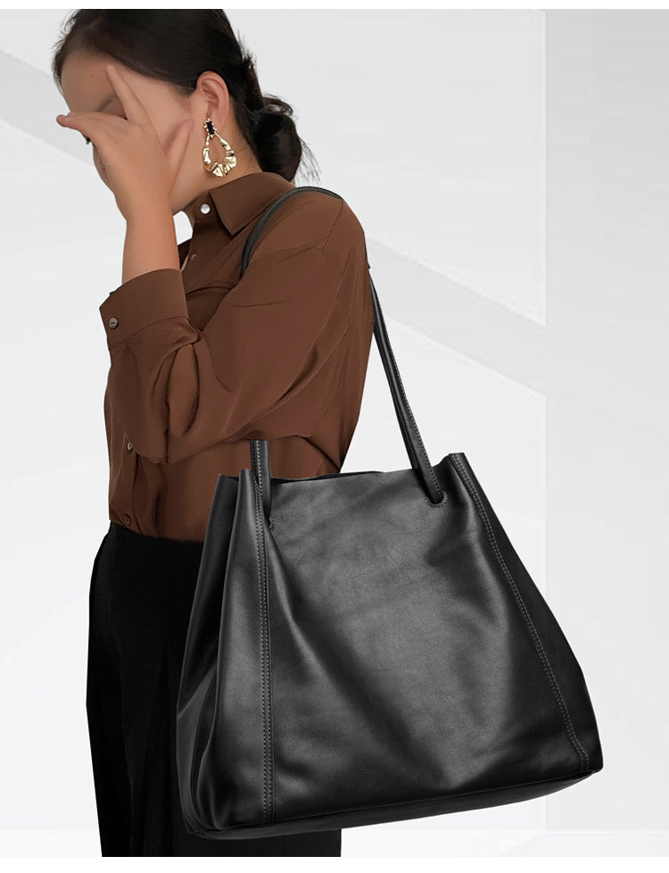 Woman holding a black leather handbag against a white background