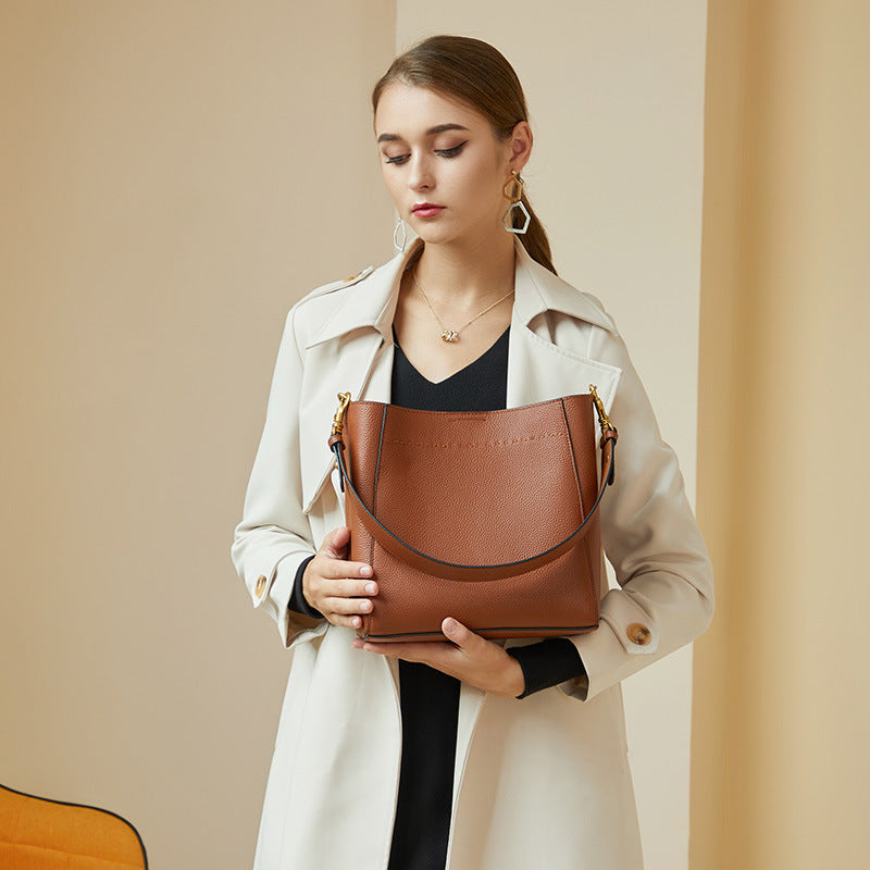Woman holding a brown leather handbag against a beige background
