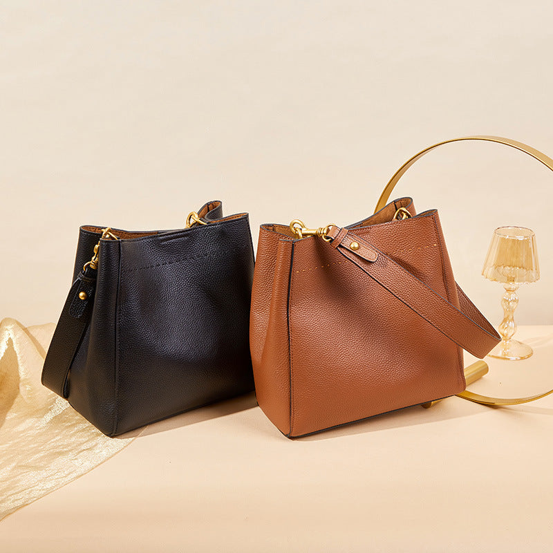 Black and brown leather handbags on a beige surface with a lamp in the background